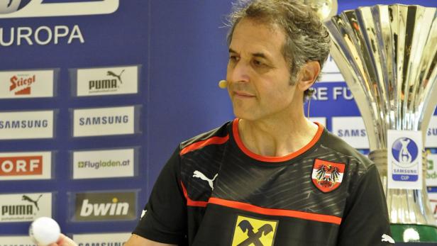 Ein Mann mit Mikrofon und Trikot des österreichischen Fußballteams vor einer Sponsorenwand.