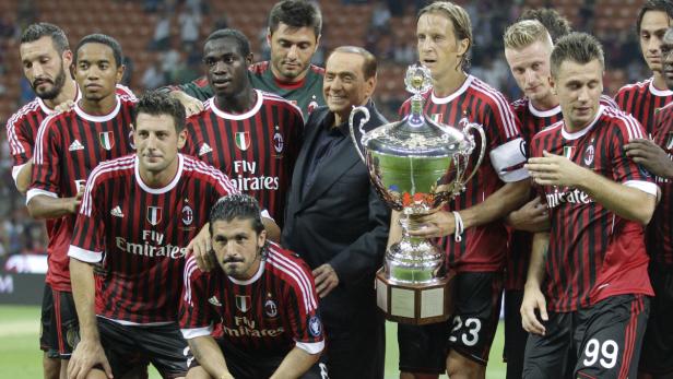 Silvio Berlusconi posiert mit der Mannschaft des AC Mailand und einem Pokal.