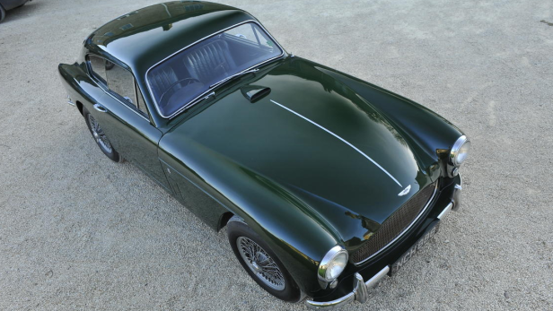 Ein grüner Aston Martin DB2/4 steht auf einem Kiesweg.