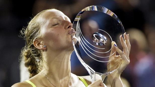 Eine Tennisspielerin küsst ihre Trophäe.