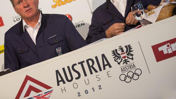 Männer am Tisch des Austria House 2012 mit Logos und österreichischen Symbolen.