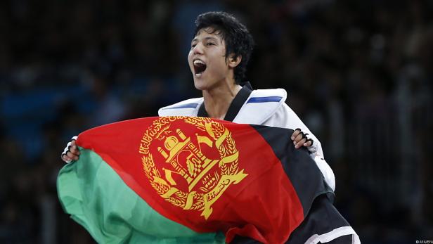 Ein Taekwondo-Sportler jubelt mit der afghanischen Flagge.