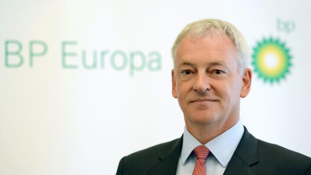 Ein Mann im Anzug steht vor einem BP Europa Logo.