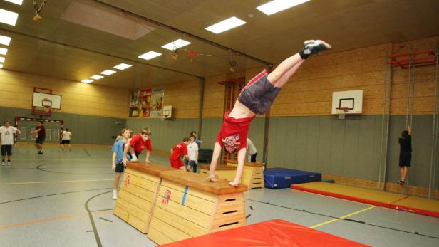 Ein Junge macht einen Handstand auf einem Turnbock in einer Turnhalle.