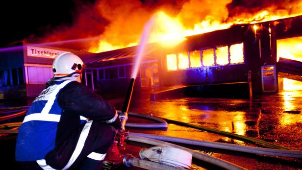 Ein Feuerwehrmann bekämpft einen Brand in einer Tischlerei.
