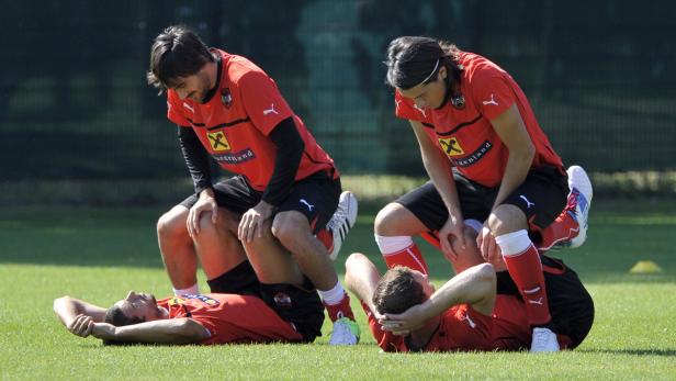 Zwei Fußballspieler dehnen die Muskeln ihrer Teamkollegen auf dem Rasen.