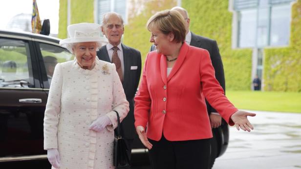 Königin Elisabeth II. und Angela Merkel treffen sich vor einem Gebäude.