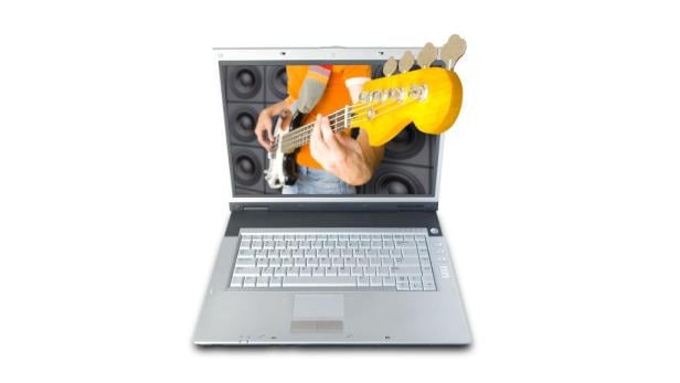 Ein Laptop zeigt einen Mann, der Bassgitarre spielt, mit Lautsprechern im Hintergrund.
