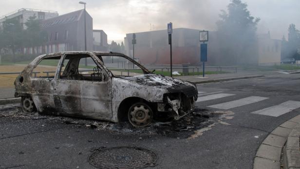 Ein ausgebranntes Auto steht auf einer Straße.