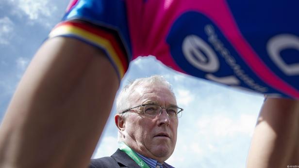 Ein Mann mit Brille blickt unter einem Radsporttrikot hindurch.