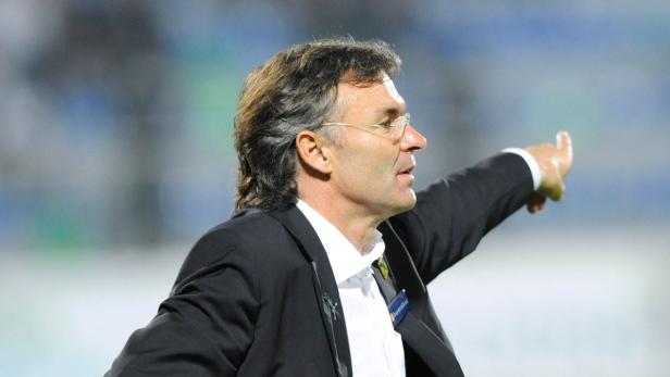 Ein Mann in Anzug und Brille zeigt mit dem Finger nach rechts.