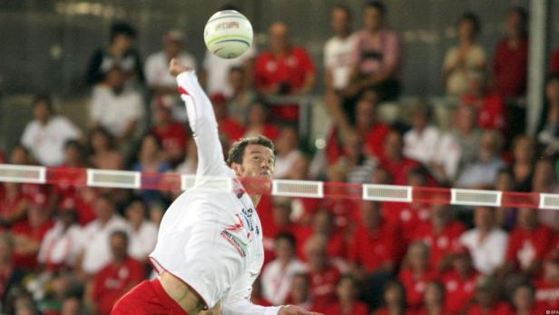 Ein Faustballspieler schlägt den Ball über das Netz.