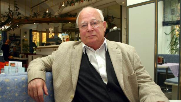 Ein älterer Mann mit Brille sitzt in einem Café.