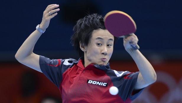 Eine Frau spielt Tischtennis und schlägt den Ball mit dem Schläger.