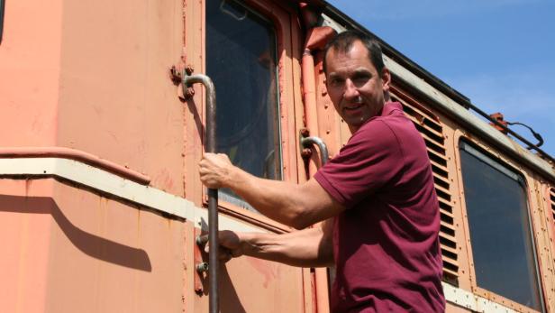 Ein Mann steigt in einen orangefarbenen Zug ein.