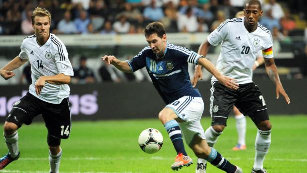 Lionel Messi dribbelt während eines Fußballspiels gegen zwei deutsche Spieler.