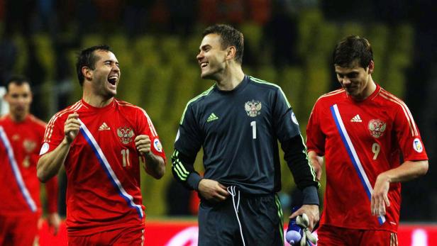 Drei russische Fußballspieler in ihren Trikots stehen zusammen und lachen.