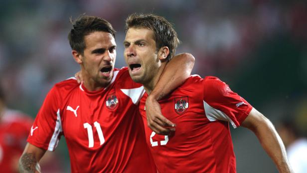 Zwei österreichische Fußballspieler jubeln in ihren roten Trikots.