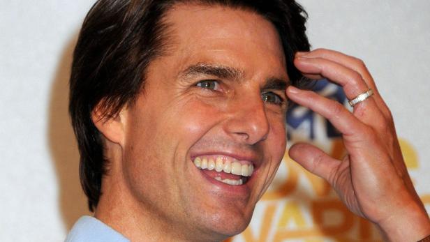 Ein lächelnder Tom Cruise mit der Hand am Kopf.