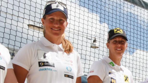 Zwei Beachvolleyballspielerinnen posieren vor einem Netz.