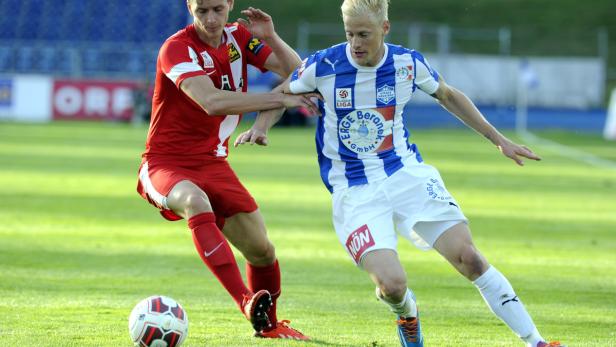 Zwei Fußballspieler kämpfen um den Ball auf dem Spielfeld.