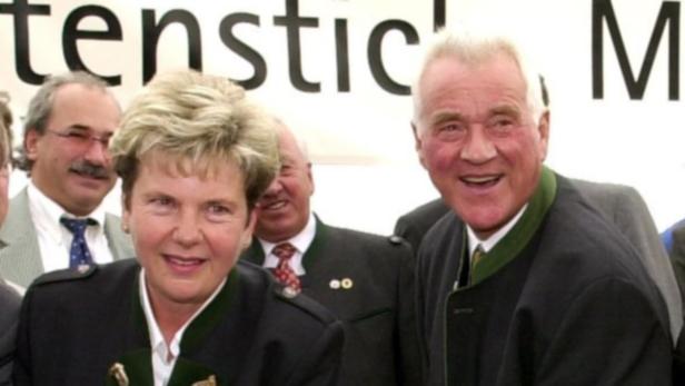 Ein Mann und eine Frau in Tracht stehen lächelnd vor einem Banner.