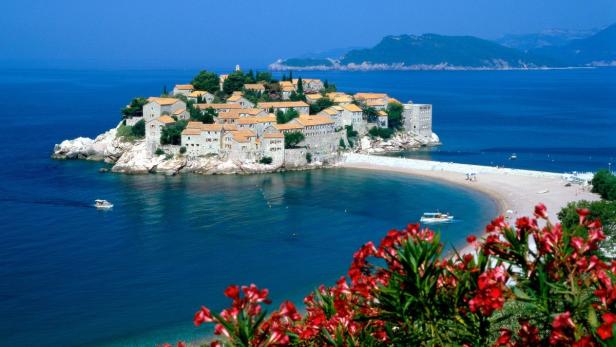 Sveti Stefan, eine kleine Insel mit Häusern und einem Strand, ist durch einen Damm mit dem Festland verbunden.