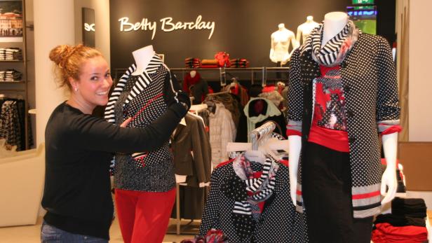 Eine Frau präsentiert Mode von Betty Barclay in einem Bekleidungsgeschäft.