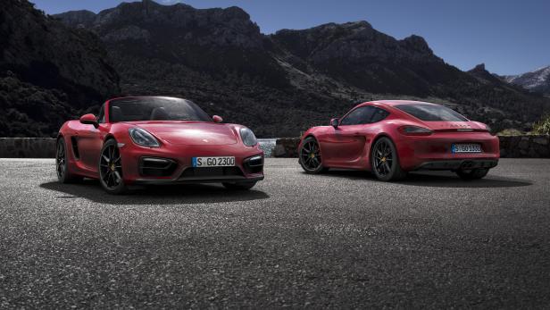 Zwei rote Porsche 718 GTS stehen vor einer Bergkulisse.