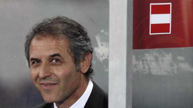 Ein Mann lächelt neben einer österreichischen Flagge.