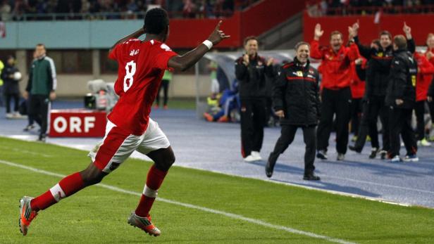 Ein Fußballspieler jubelt mit erhobenen Armen auf dem Spielfeld.