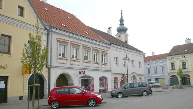 Ein Platz mit geparkten Autos und einem BIPA-Geschäft in einer österreichischen Stadt.