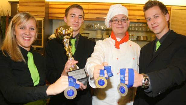 Eine Gruppe junger Leute präsentiert stolz einen Pokal und Medaillen.
