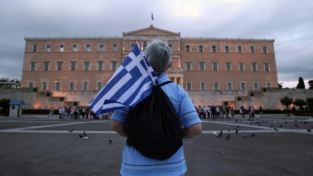 Eine Person mit griechischer Flagge vor dem griechischen Parlament in Athen.