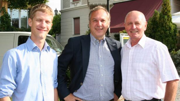 Drei Männer posieren vor einem Gebäude für ein Foto.