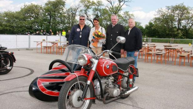 Eine rote BMW-Motorrad mit Beiwagen steht vor einer Gruppe von vier Personen.