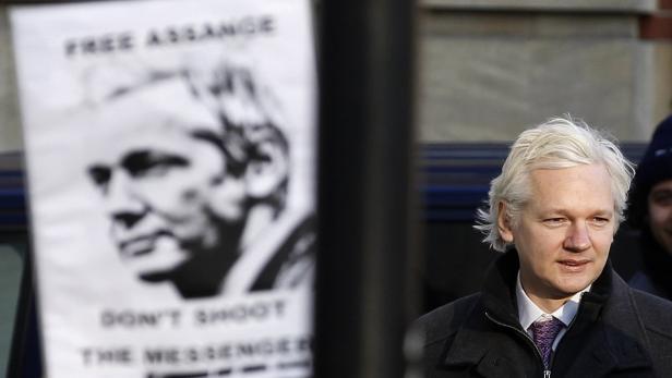 Julian Assange vor einem Plakat mit der Aufschrift „Free Assange“.