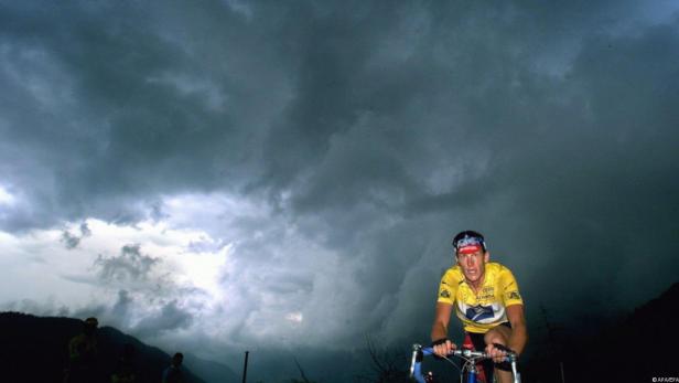 Ein Radfahrer fährt vor einem dunklen, bewölkten Himmel.