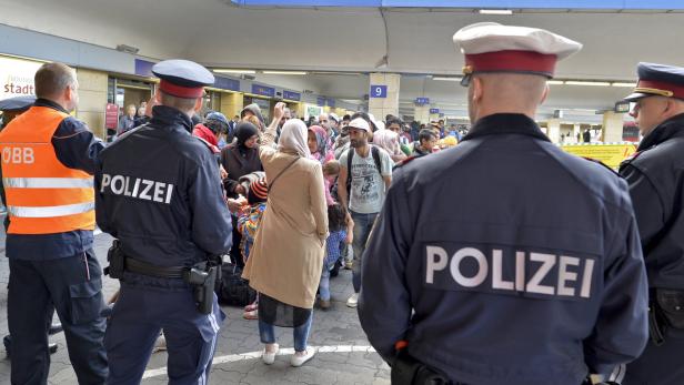 Polizisten beobachten eine Menschenmenge in einer Bahnhofshalle.
