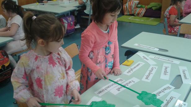 Zwei Mädchen spielen mit einer Wortschatz-Fänger-Spiel im Klassenzimmer.