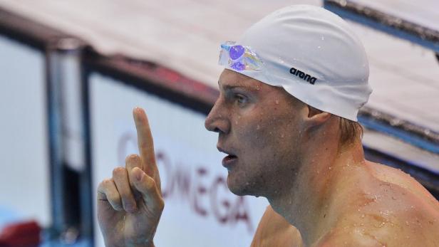 Ein Schwimmer mit Badekappe und Schwimmbrille reckt den Zeigefinger in die Höhe.