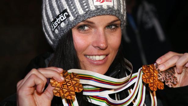 Eine Frau mit Mütze hält zwei Medaillen mit Schneeflocken-Motiv in den Händen.