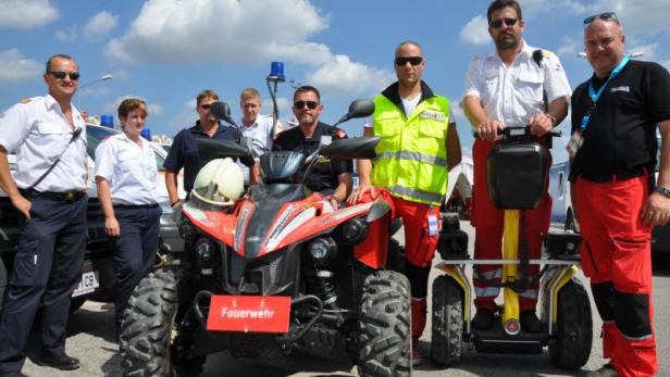 Eine Gruppe von Feuerwehrleuten steht neben einem Quad und einem Segway.