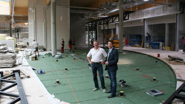 Zwei Männer stehen auf einer grünen Fläche in einem Gebäude im Bau.