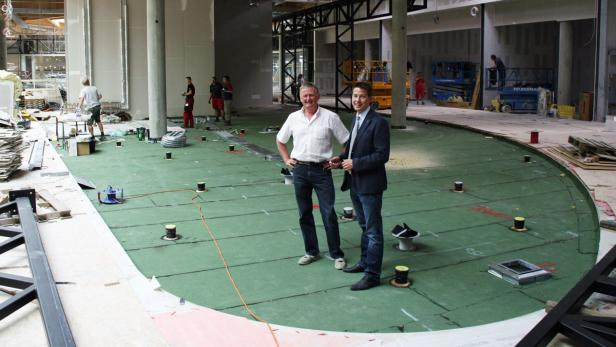 Zwei Männer stehen auf einer grünen Fläche in einem Gebäude im Bau.