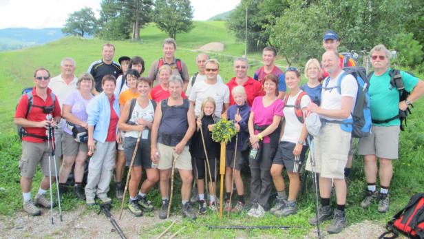 Eine Gruppe Wanderer posiert auf einer grünen Wiese für ein Foto.