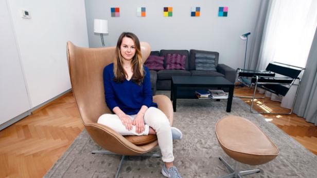 Eine Frau sitzt in einem Ledersessel in einem Wohnzimmer.