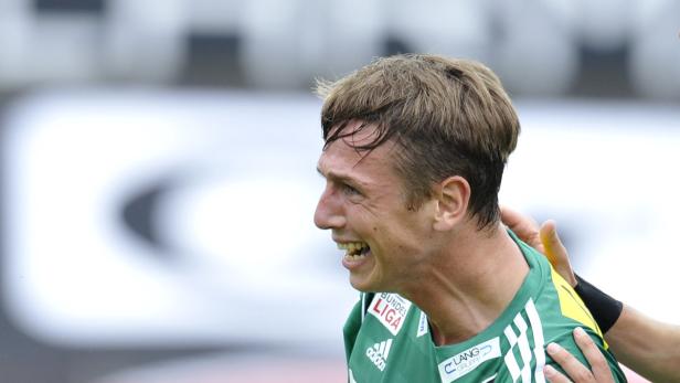 Ein Fußballspieler in einem grünen Trikot jubelt auf dem Spielfeld.