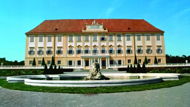 Schloss Hof mit einem Brunnen im Vordergrund an einem sonnigen Tag.