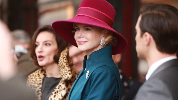 Nicole Kidman mit einem roten Hut und einem grünen Mantel bei einer Veranstaltung.